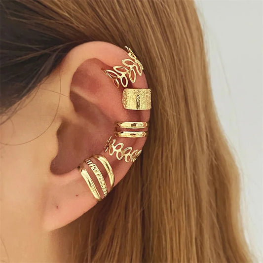 Une oreille ornée de plusieurs bagues d'oreille dorées aux designs variés.