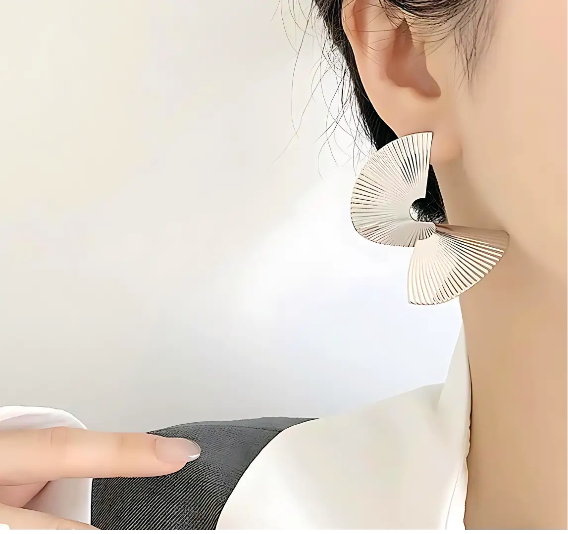 boucles d'oreilles en forme d'éventail, argentées et symétriques, sont disposées face à face sur un fond blanc, ajoutant une touche élégante et moderne.