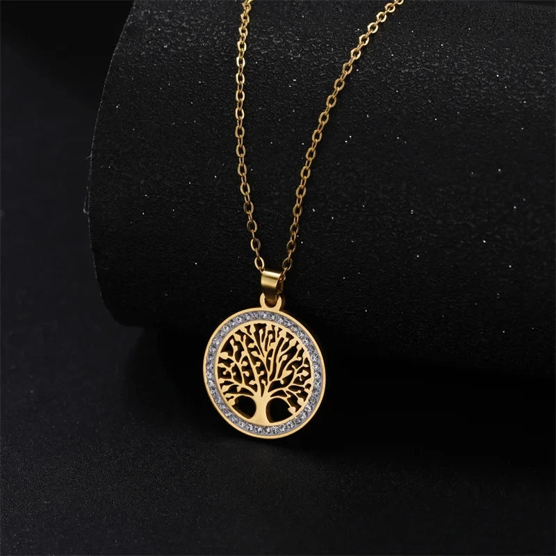 Collier Auréa de Rue des Bijoux, en acier inoxydable doré de haute qualité. Il présente une chaîne à mailles délicates et un pendentif en forme d'arbre de vie, orné de brillantes pierres de zircon cubique, symbolisant la croissance et la connexion à la nature.