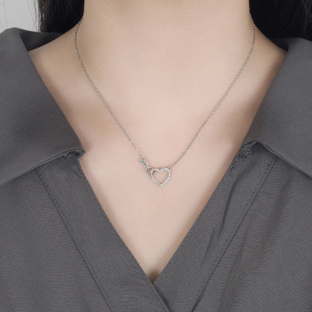 Une femme portant le collier Dina en argent sterling 925, avec un pendentif en forme de cœur serti de pierres de zircon cubique, suspendu à une chaîne fine en argent.